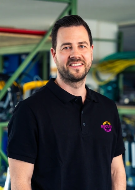 Mann mit Recupo-Polo vor Lagerregalen.